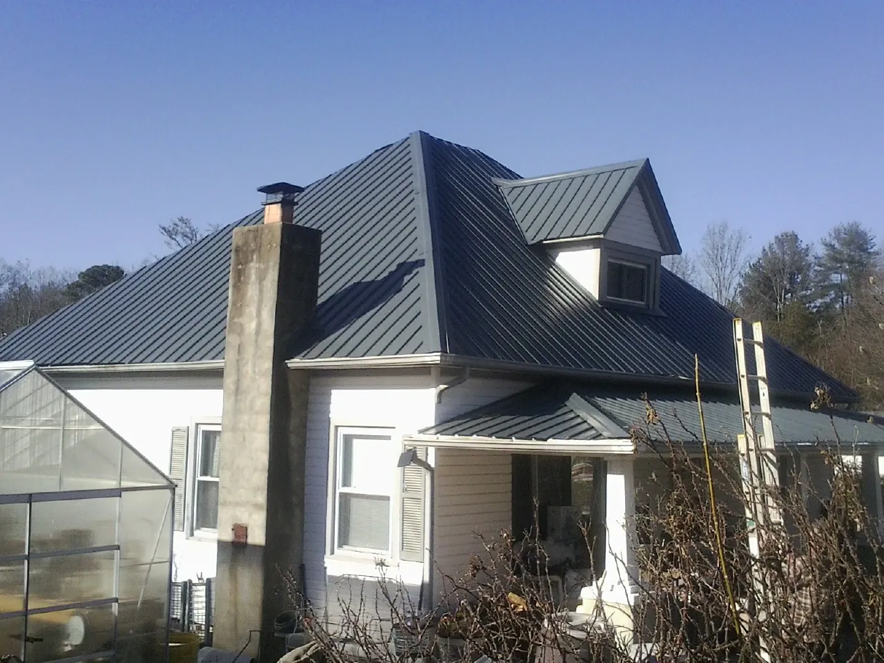 Dark blue standing seam metal roof on a white farmhouse with dormer — Slate & Tile Roof Repair by Roofing Brothers in Pisgah Forest