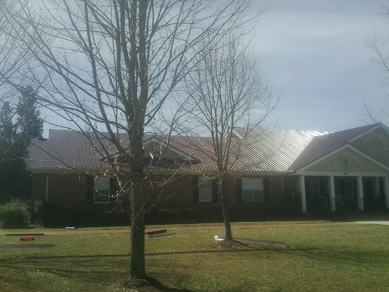 Red metal roof on a brick building seen from the front lawn in Pisgah Forest