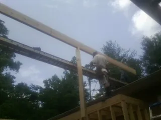 Carpenter setting a ridge beam over a new addition frame — Ice Dam Removal by Roofing Brothers in Pisgah Forest