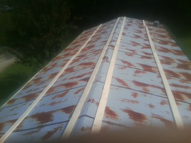 Rusted metal roof panels with new wood purlins before replacement — Storm Damage Roof Repair in Pisgah Forest by Roofing Brothers