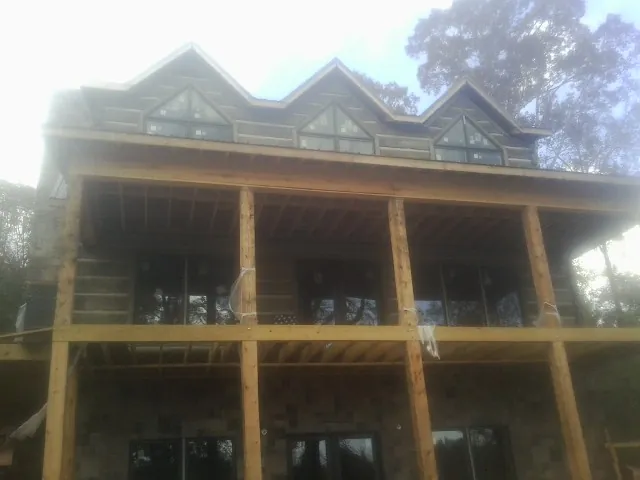 Dormers and porch framing on a large log home under construction — Roof Coating work by our crew in Pisgah Forest