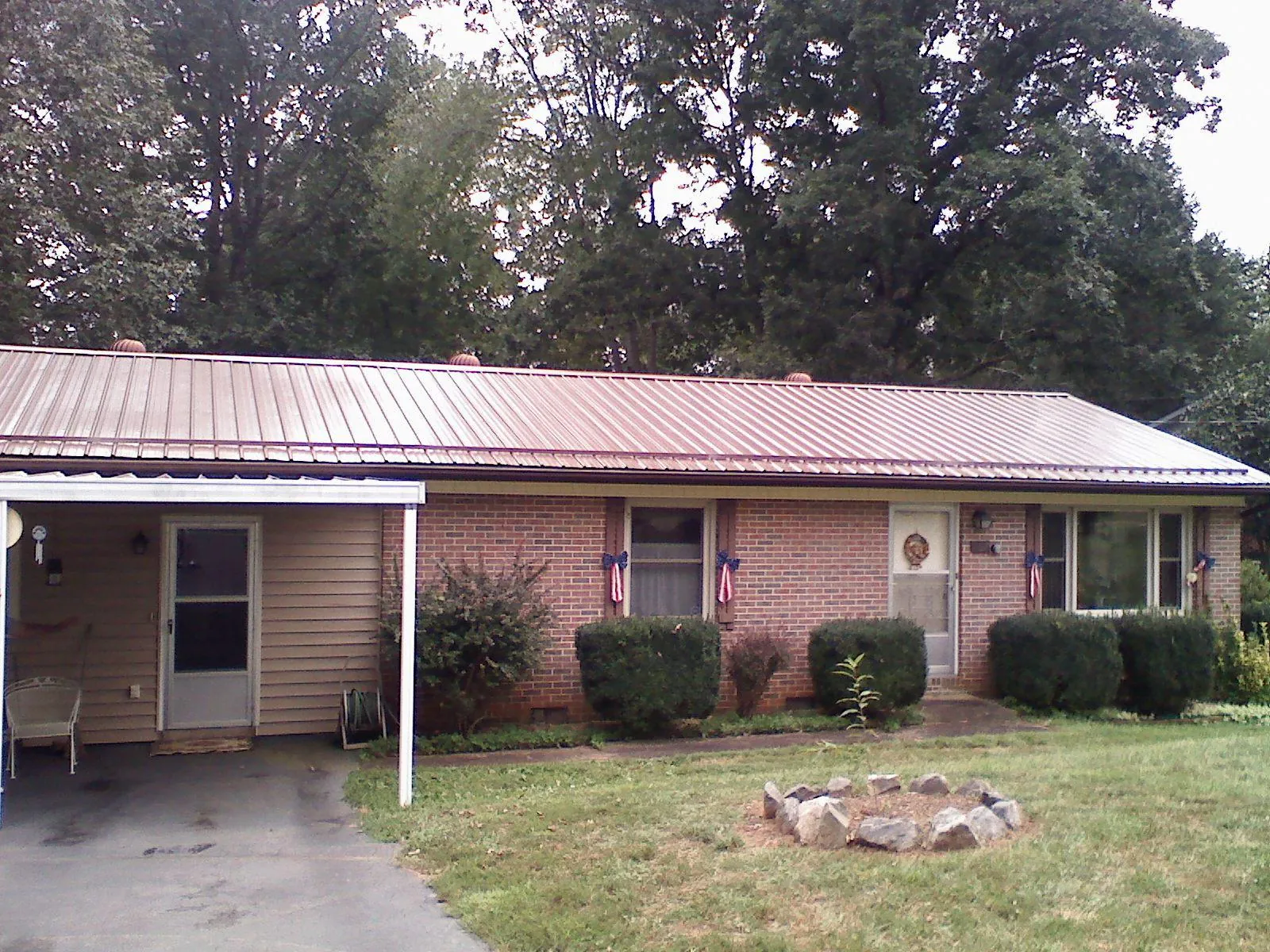 Bronze metal roof and carport on a brick ranch home — Roof Repair work by our crew in Pisgah Forest