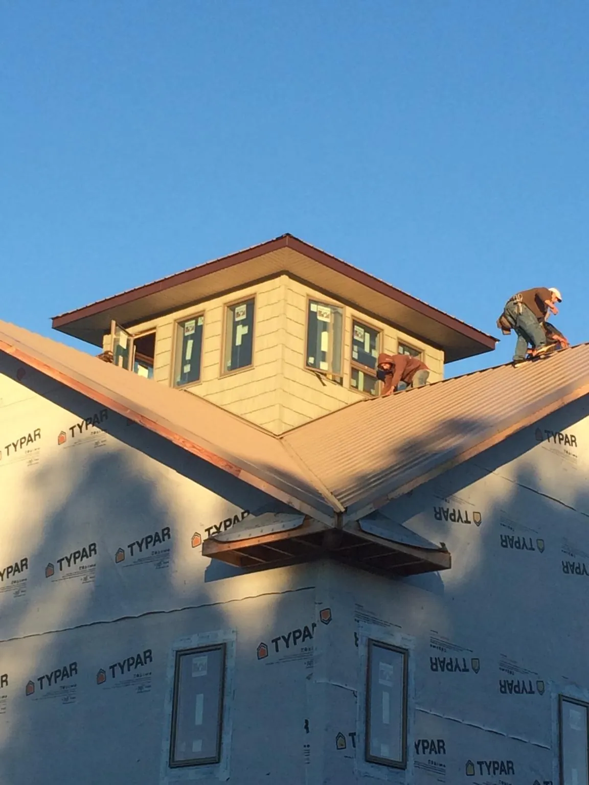Roofers working around a rooftop cupola on a new metal roof at sunset — Roof Waterproofing in Pisgah Forest by Roofing Brothers
